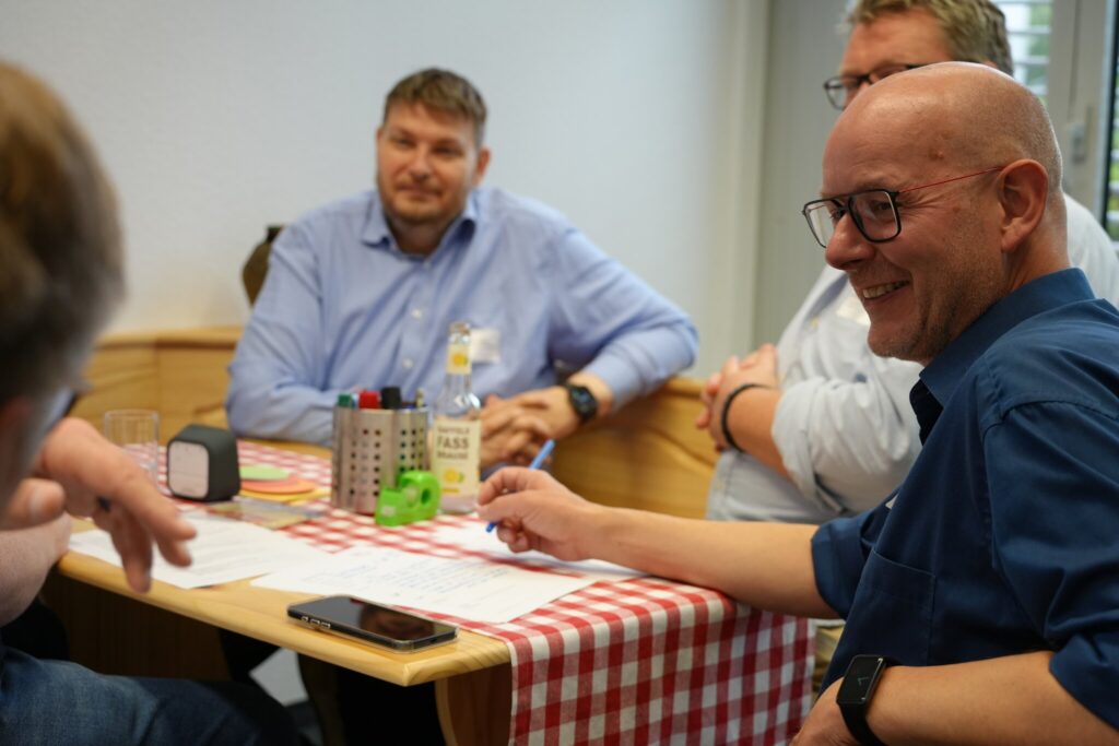 Kleine Runde am Tisch mit karierter Tischdecke während einer Barcamp-Session.